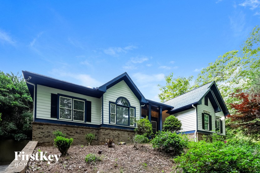 front view of a green and white house with black trim and a blue roof
