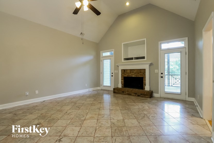 an empty living room with a fireplace and a ceiling fan