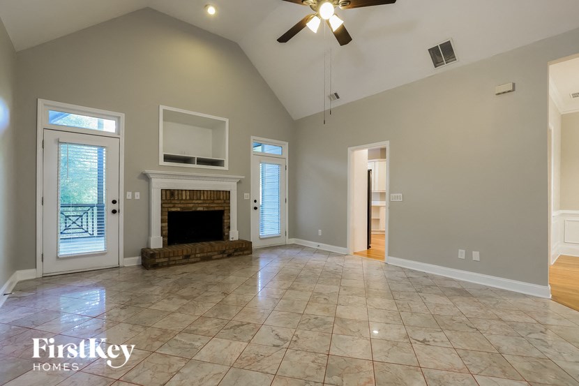 an empty living room with a fireplace and a ceiling fan