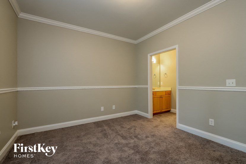 a bedroom with a carpeted floor and a door to a bathroom