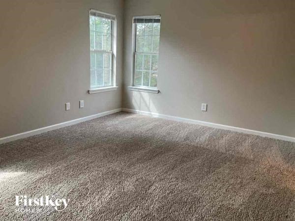 an empty room with a carpeted floor and two windows