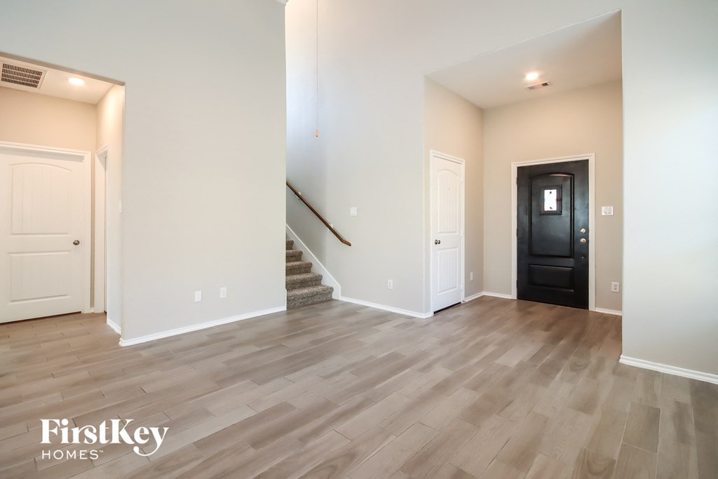 the living room and entryway of an empty house with white walls and wood floors