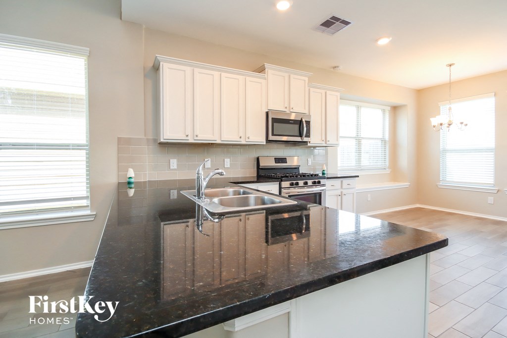 a kitchen with white cabinets and a black counter top