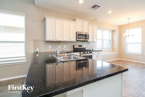 a kitchen with white cabinets and a black counter top