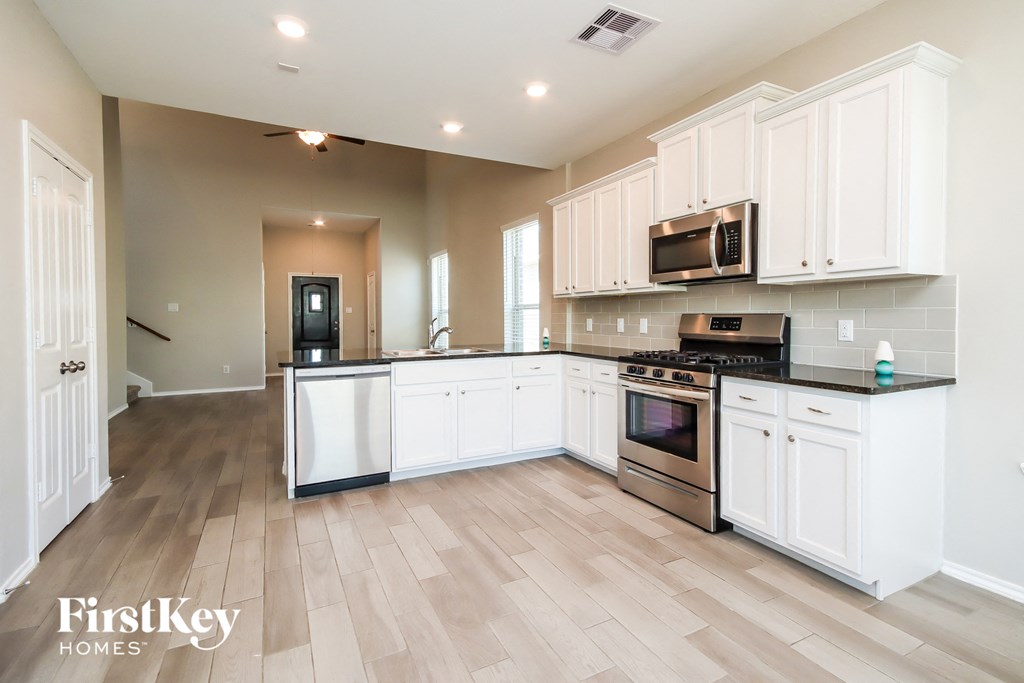a large kitchen with white cabinets and stainless steel appliances