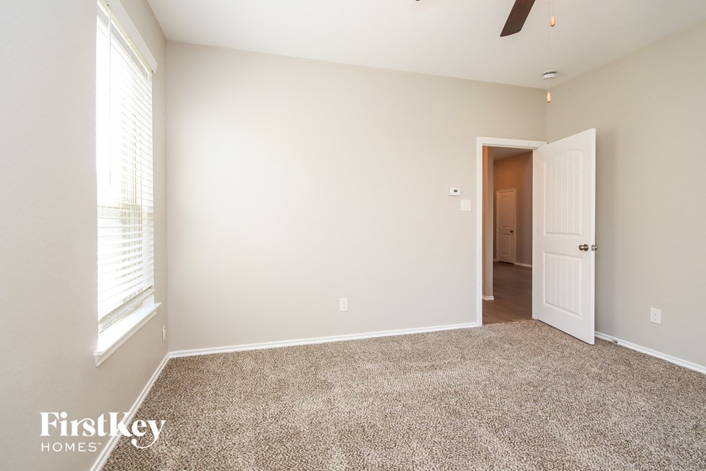 a bedroom with a carpeted floor and a door to a hallway