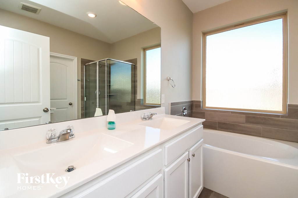 a bathroom with two sinks and a tub and a shower