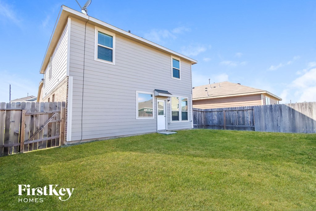 a backyard with a white house and a fence