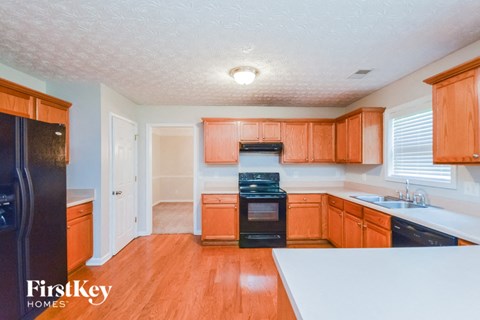 a kitchen with wooden cabinets and black appliances and white counter tops