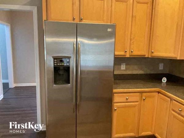 A stainless steel refrigerator in a kitchen with wooden cabinets.