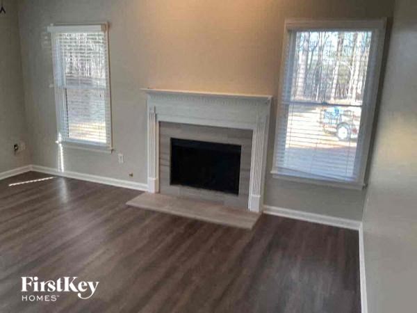 A living room with a fireplace and two windows.