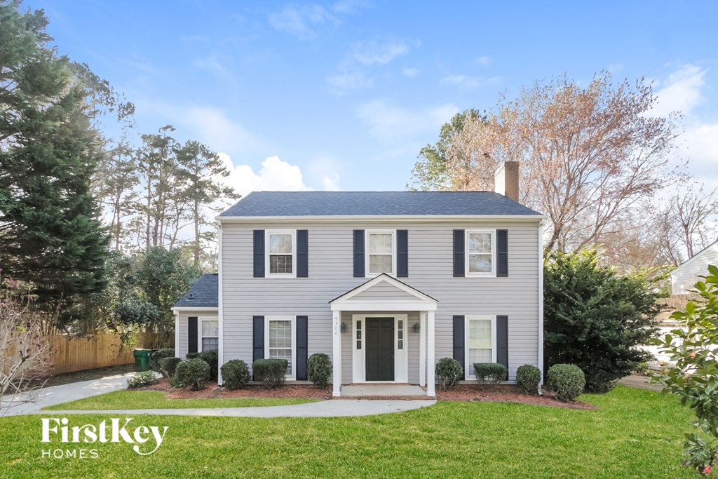 a white house with black shutters and a lawn and trees