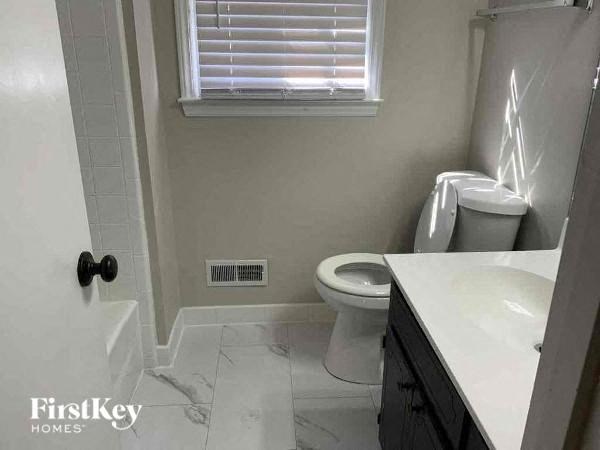 a bathroom with a toilet and a sink and a window
