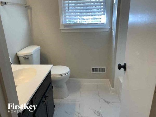 a bathroom with a toilet and a sink and a window