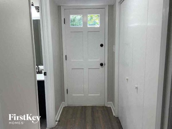 a hallway with a white door and a bathroom