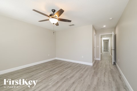 a spacious living room with hardwood floors and a ceiling fan