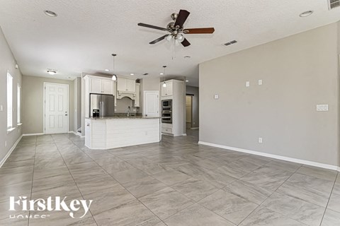 an empty kitchen and living room with a ceiling fan