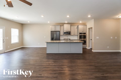 A spacious kitchen with a center island and a ceiling fan.
