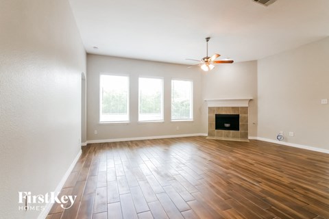 the living room with wood floors and a fireplace