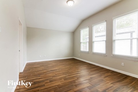 the spacious living room with hardwood flooring and three windows