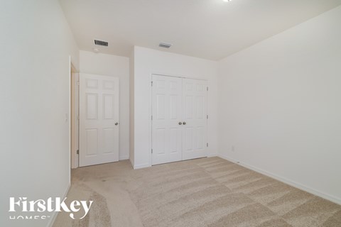 A bedroom with two doors and a carpeted floor.