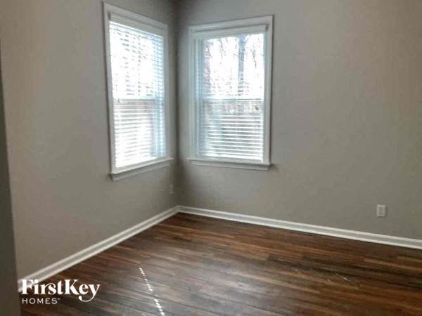 a empty room with wood floors and two windows
