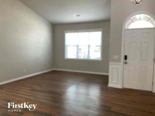 an empty living room with a white door and a window