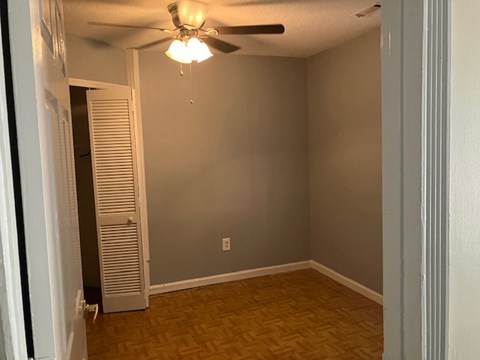 A room with a ceiling fan and a door.