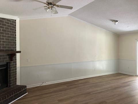 A room with a fireplace and wood flooring.