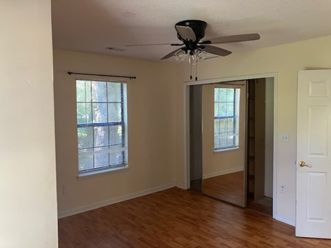 A room with a ceiling fan and a mirrored door.