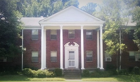 a red brick house with white columns and a white door