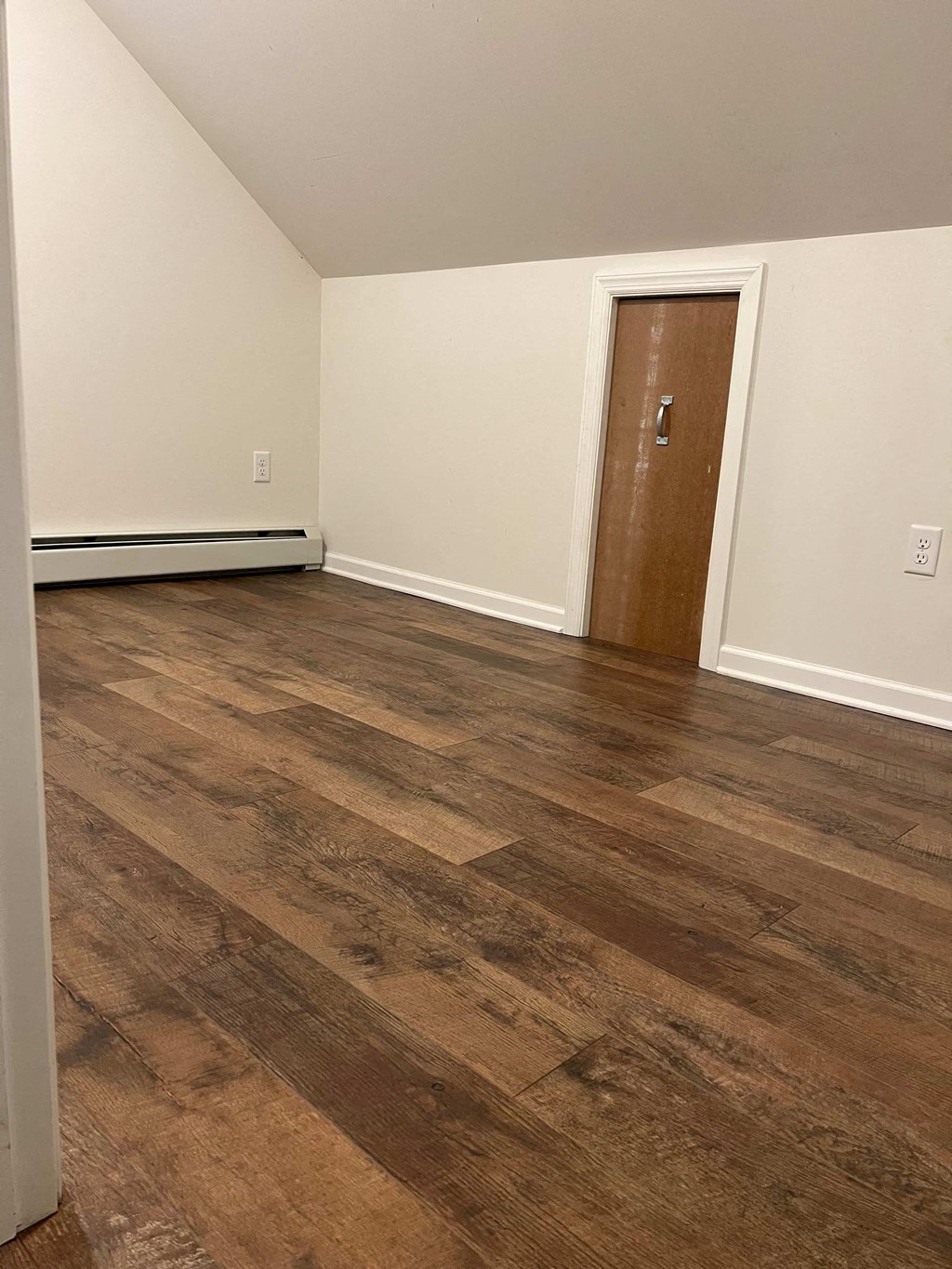 an empty room with wooden floors and a door
