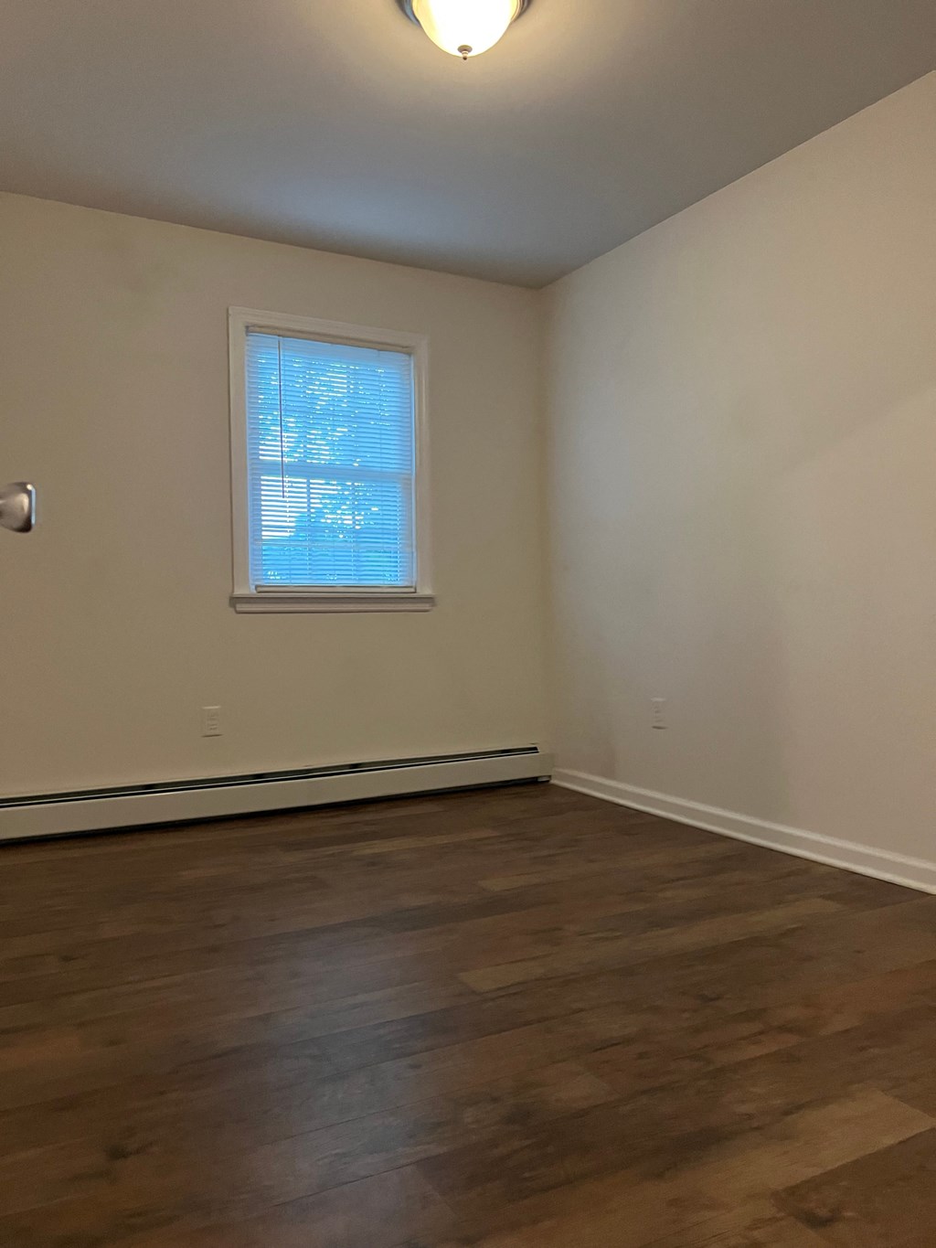 an empty living room with wooden floors and a window