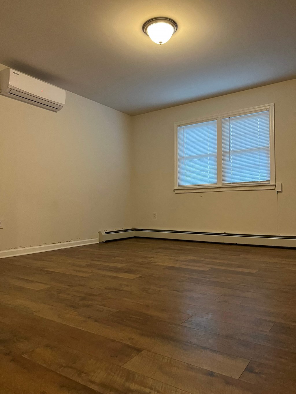 an empty living room with wooden floors and a window