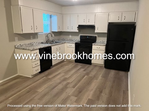 A kitchen with black appliances and white cabinets.