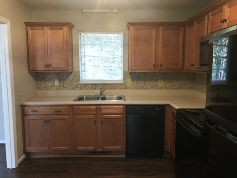 A kitchen with wooden cabinets and black appliances.