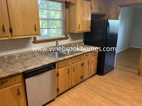A kitchen with wooden cabinets and a black fridge.