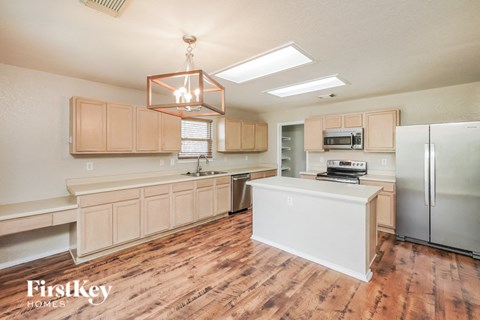 A kitchen with wooden floors and a white fridge.