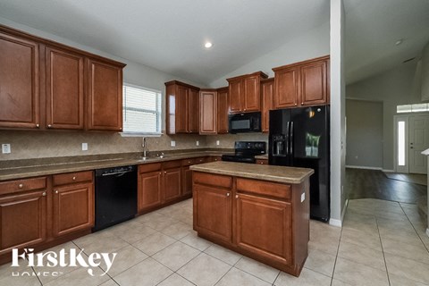 A kitchen with wooden cabinets and a black fridge.