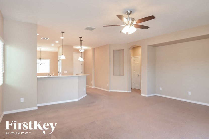 A spacious room with a ceiling fan and lighting fixtures.