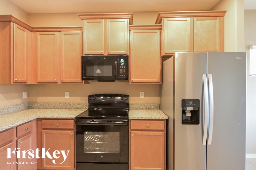 A kitchen with wooden cabinets and a black microwave.