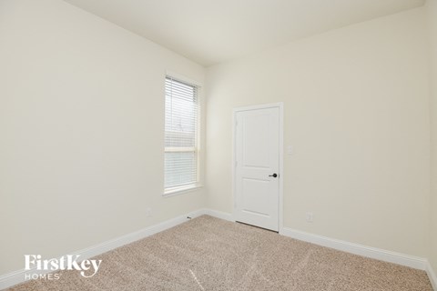 a bedroom with a door and a window and a carpeted floor