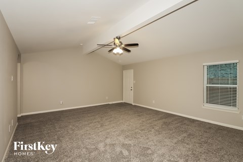 A spacious room with a ceiling fan and carpeted floor.