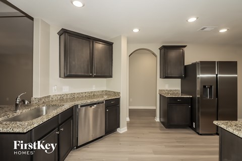 A kitchen with a sink, cabinets, and a refrigerator.