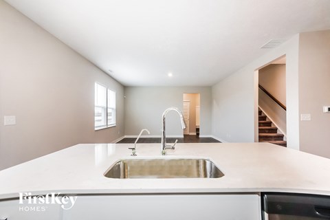 A modern kitchen with a stainless steel sink and a white countertop.