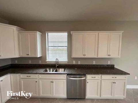 A kitchen with white cabinets and a black countertop.