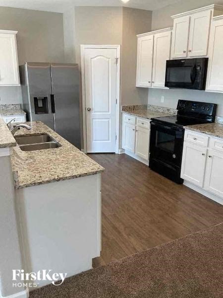 a kitchen with white cabinets and black appliances