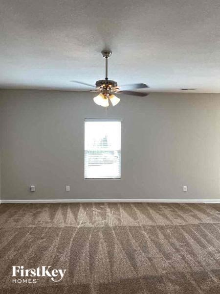 an empty living room with a ceiling fan and a window