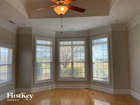 a living room with a ceiling fan and four windows