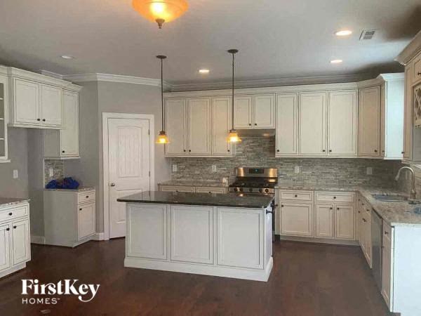 a kitchen with white cabinets and a black counter top